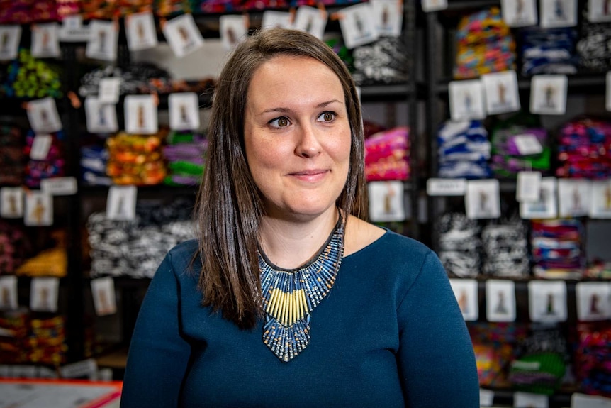 Laura O'Reilly looks out into the distance with clothing samples in the background on shelves.