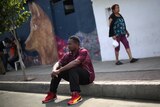 Normilus Mondesir sits on the curb outside his shelter in Tijuana.