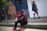 Normilus Mondesir sits on the curb outside his shelter in Tijuana.