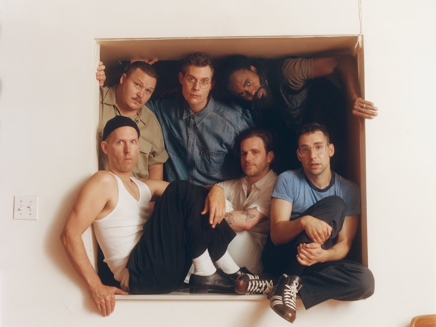 A 2024 press shot of indie rock band Bleachers, fronted by Jack Antonoff, boxed into a wall window