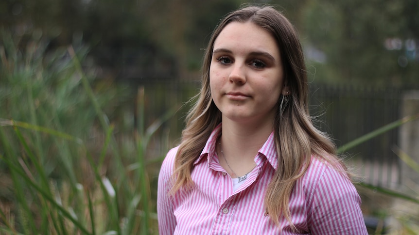 A young woman with blonde and brown hair wearing a pink shirt