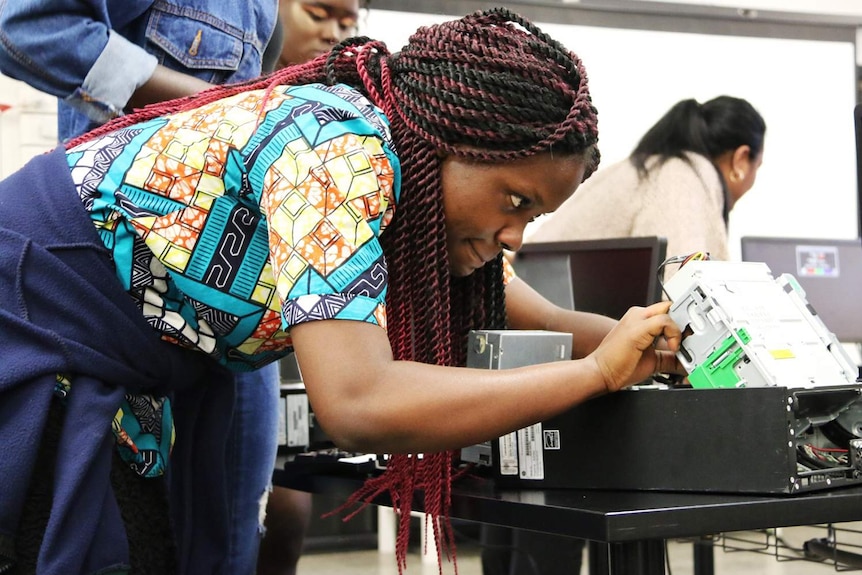 A female student works on building a computer at a workshop at the State Library of Queensland.