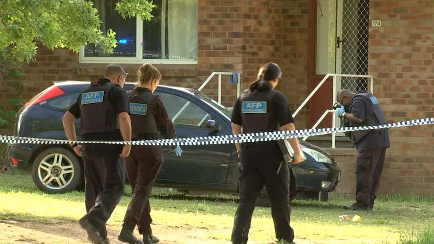 Police officers outside a brick home.