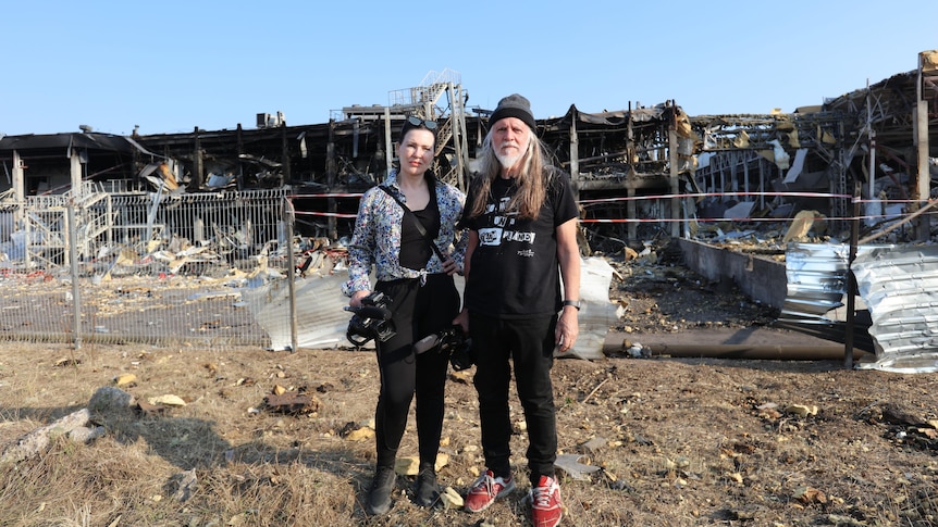 George Gittoes and his wife Helen stand in front of rubble in Odessa, Ukraine.
