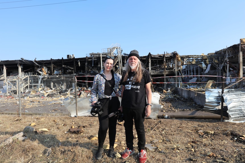 George Gittoes and his wife Helen stand in front of rubble in Odessa, Ukraine.