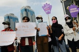Women hold up placards at a protest.