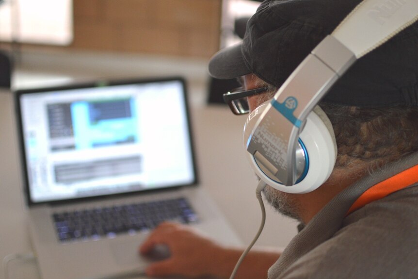 A man wearing headphones looking at a computer.