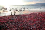 A massive crowd of supporters holding Turkish flags gather near the bay.