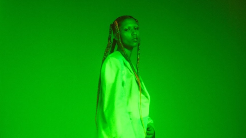 Lava La Rue stands in a room flooded with green light