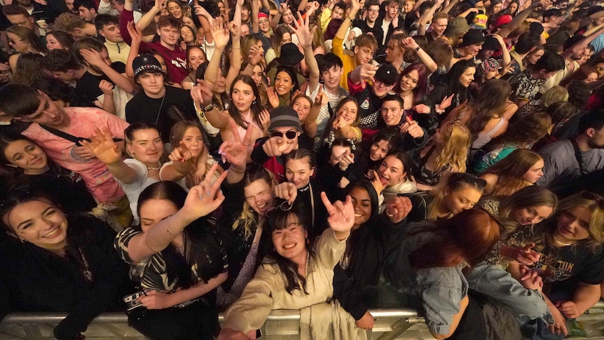 A tightly packed crowd of people dance 