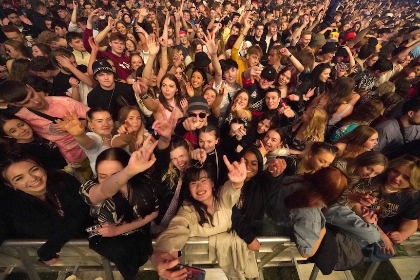 A tightly packed crowd of people dance 