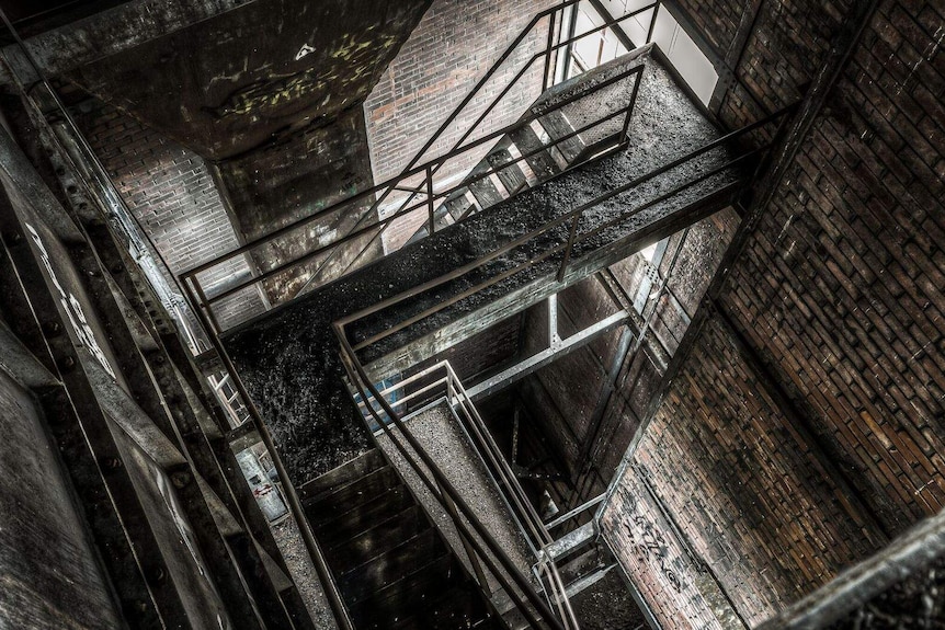 A photograph of blacks and browns looking down on a series of staircases in an abandoned building