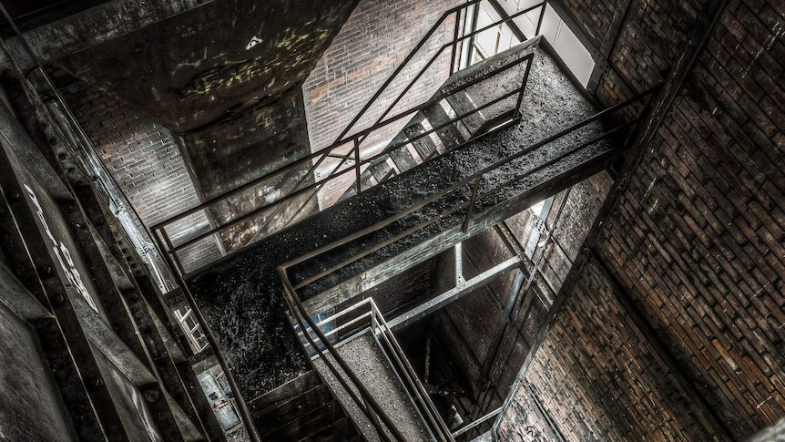 A photograph of blacks and browns looking down on a series of staircases in an abandoned building