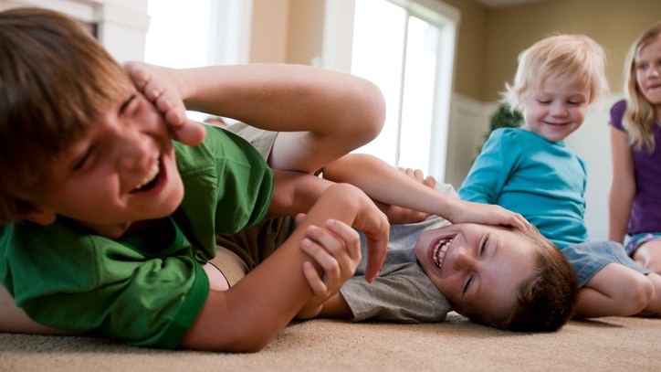 Two young boys play fighting with other young children looking on