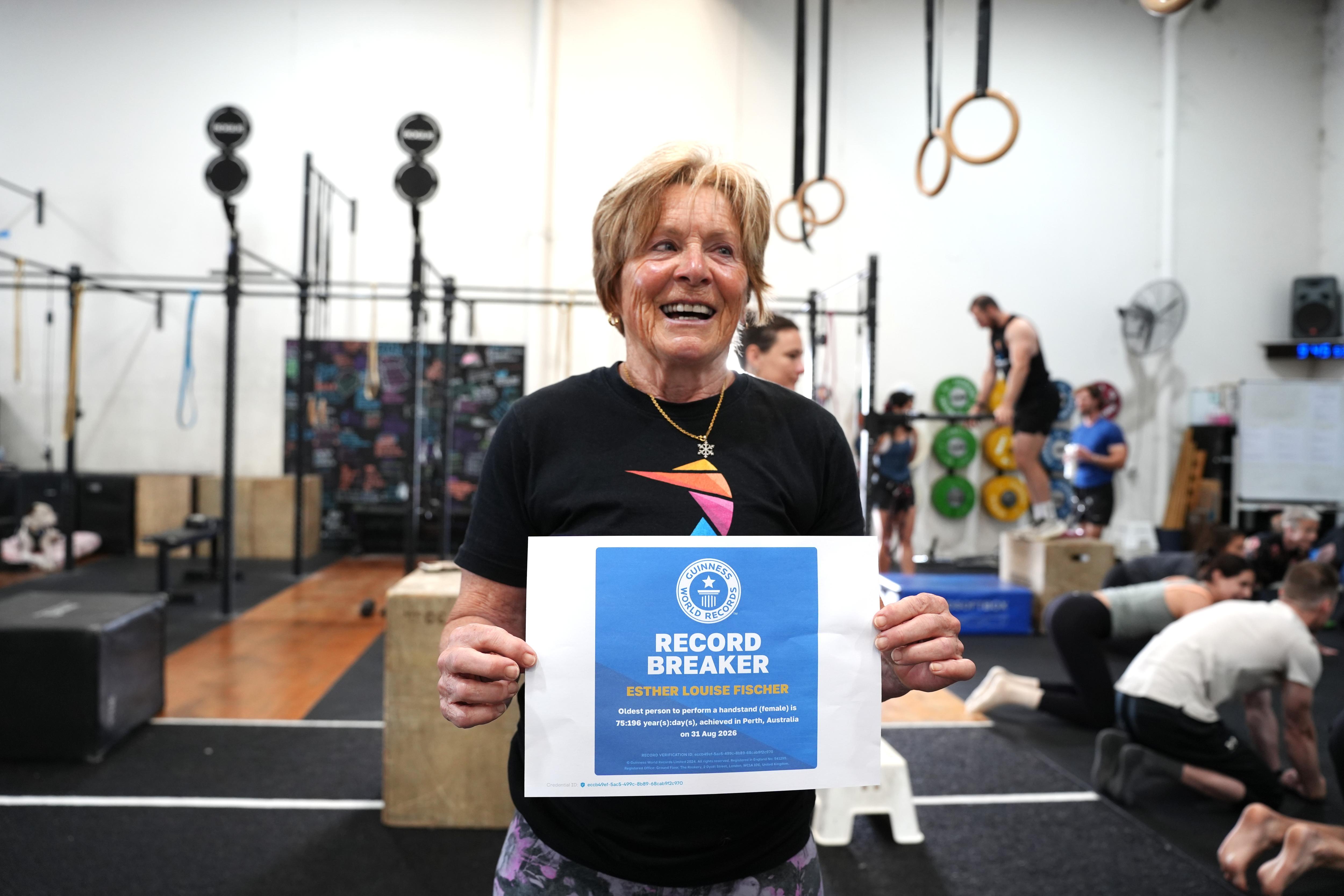 Woman with short hair smies while holding certificate that says 'record breaker' 
