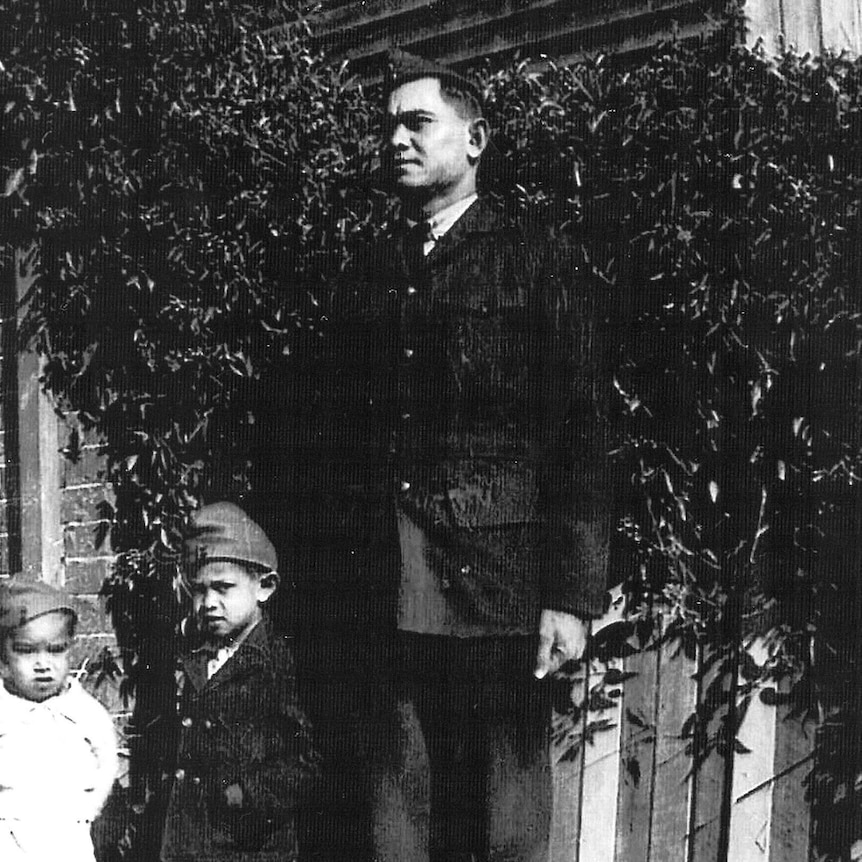 A black and white image of a WW2 soldier with two children 