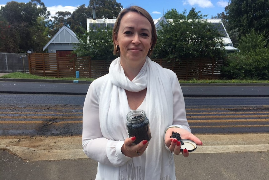 Nerida Mortlock, General Manager of Close the Loop Australia, holds a jar of the plastic and glass road surface additive.