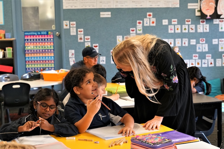 A young Syrian girl speaking with her teacher in an Australian classroom