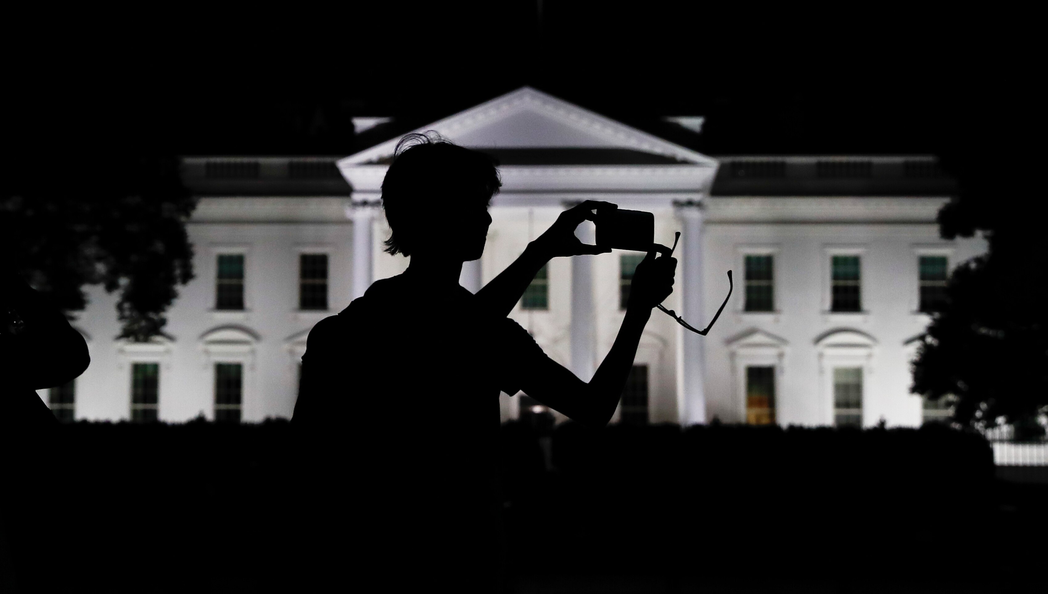 A tourist in front of the White House at night