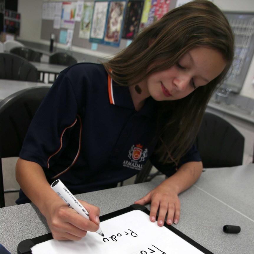 Armadale Senior High School student Hanna Nicholls sitting at a desk writing on a mini whiteboard.