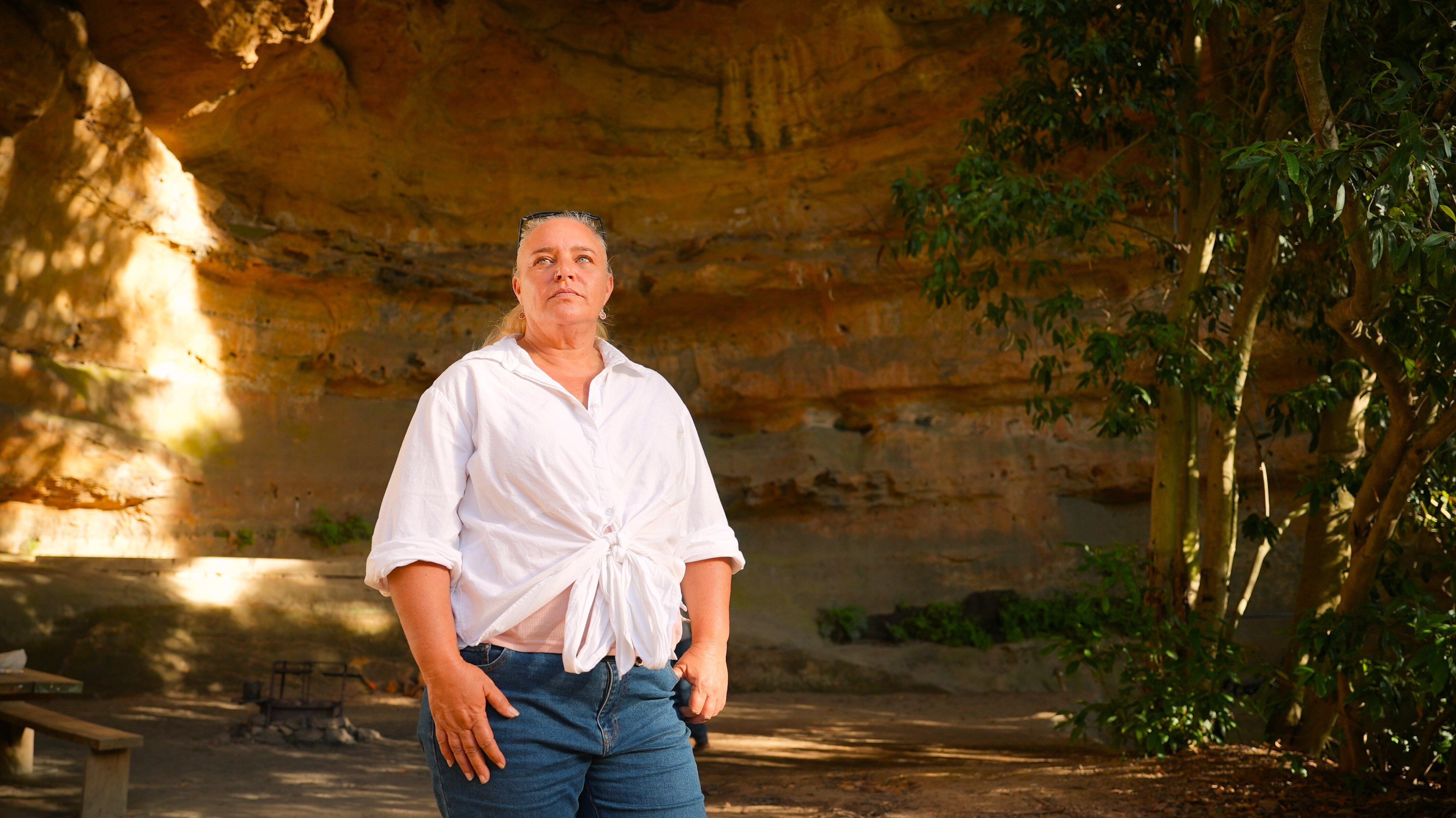 A woman stands inside a cave.