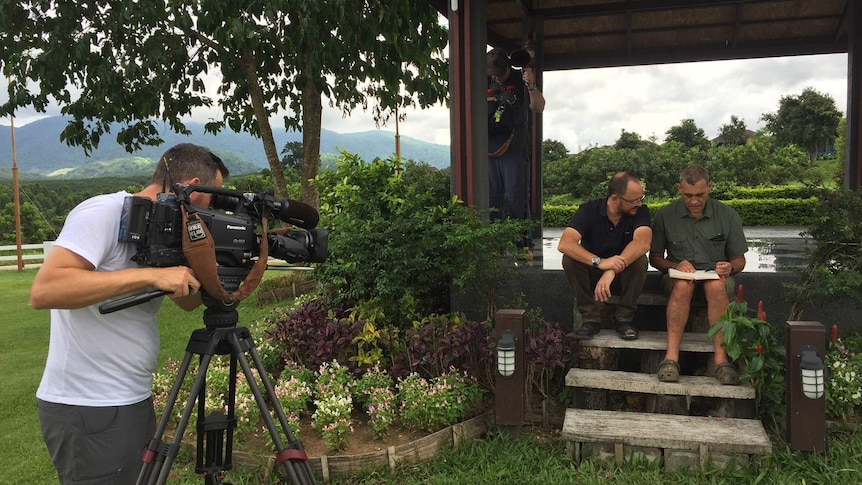 Cameraman filming Willacy sitting next to Challen on steps.