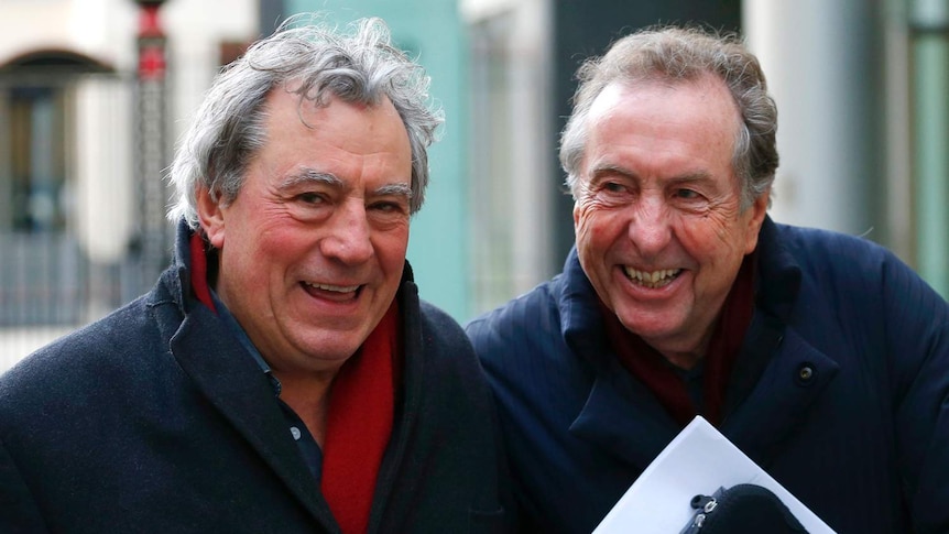Monty Python members Eric Idle (R) and Terry Jones smiling and laughing as they leave London's High Court together.