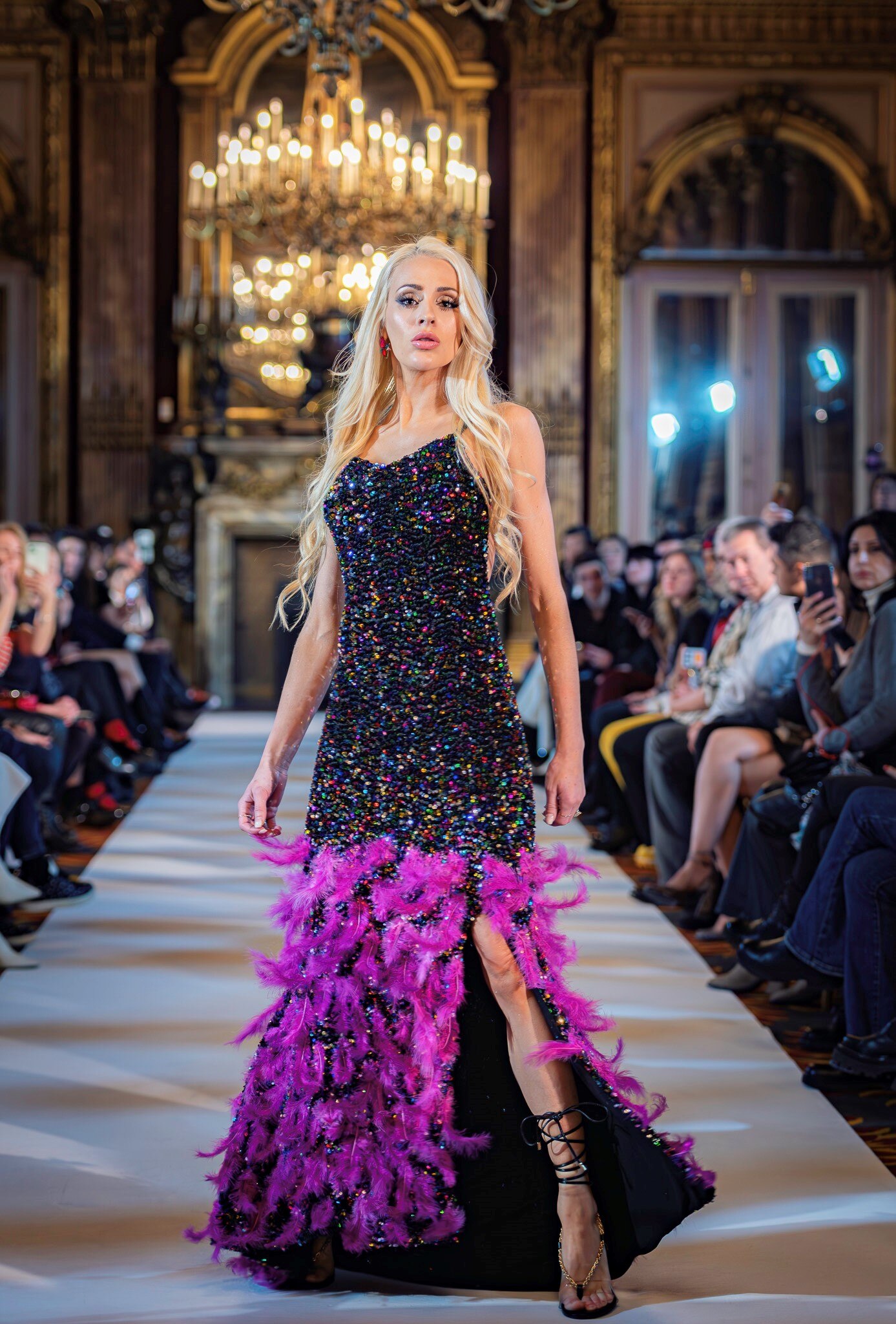 woman standing on catwalk in black and purple dress with heels