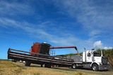 A harvester shoots rice into the back of a truck.