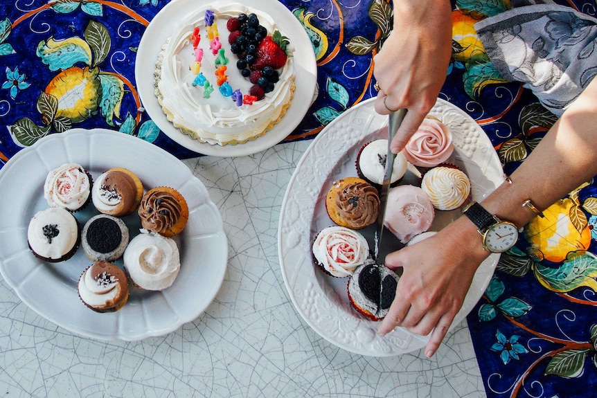 A hand cutting cupcakes on a plate