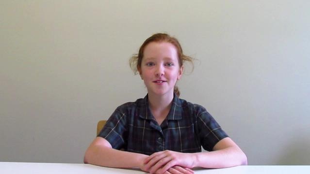 Teenage girl sits behind desk