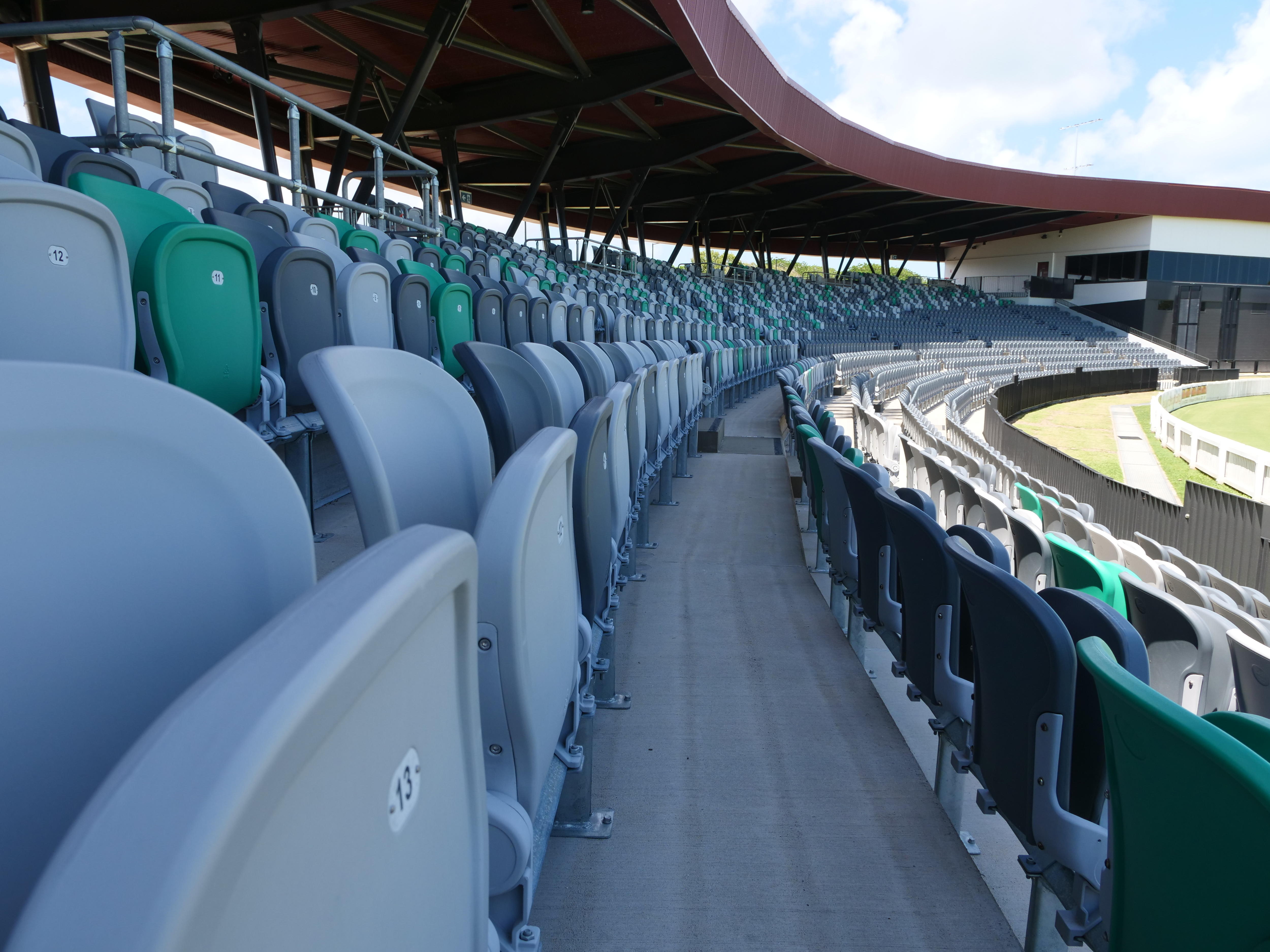 Los asientos de las gradas rodean una cancha con una cabina de transmisión al fondo. 
