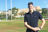 Justin Clarke standing on an AFL oval at the University of Queensland