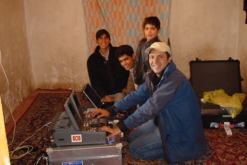 Eroglu operating portable editing equipment with three young men watching on and smiling at camera.