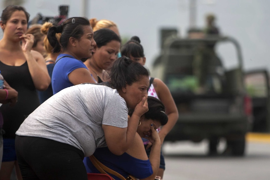Garcia residents watch the scene where gunmen stormed a beer hall and killed 10 people in Nuevo Leon state Mexico in the industrial city of Monterrey, thought to be linked to Zetas drug cartel.