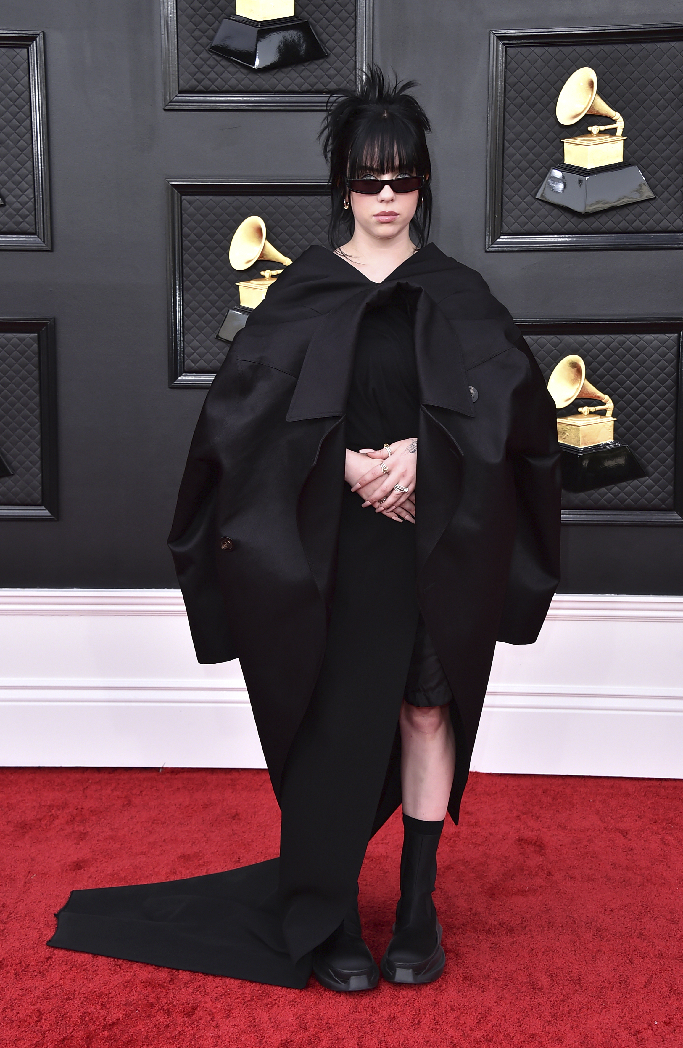 billie eilish on the red carpet wearing a long black cloak and black sunglasses