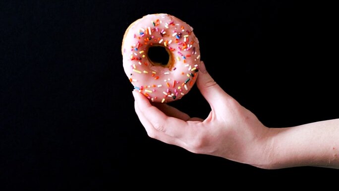 A hand holds a donut.