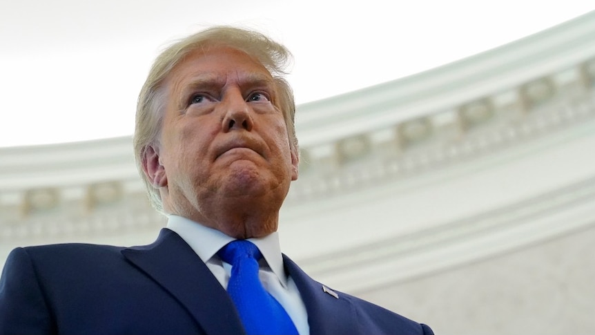 President Donald Trump listens to a reporter's question