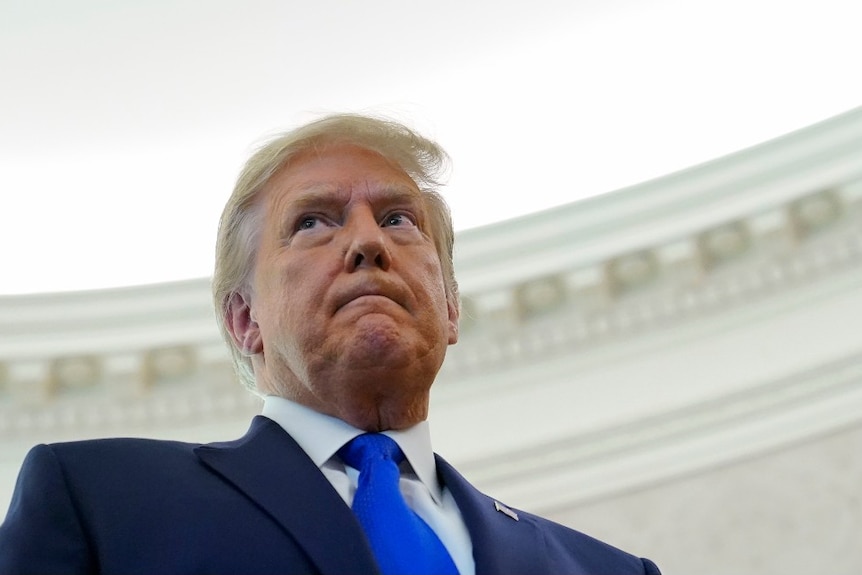 President Donald Trump listens to a reporter's question