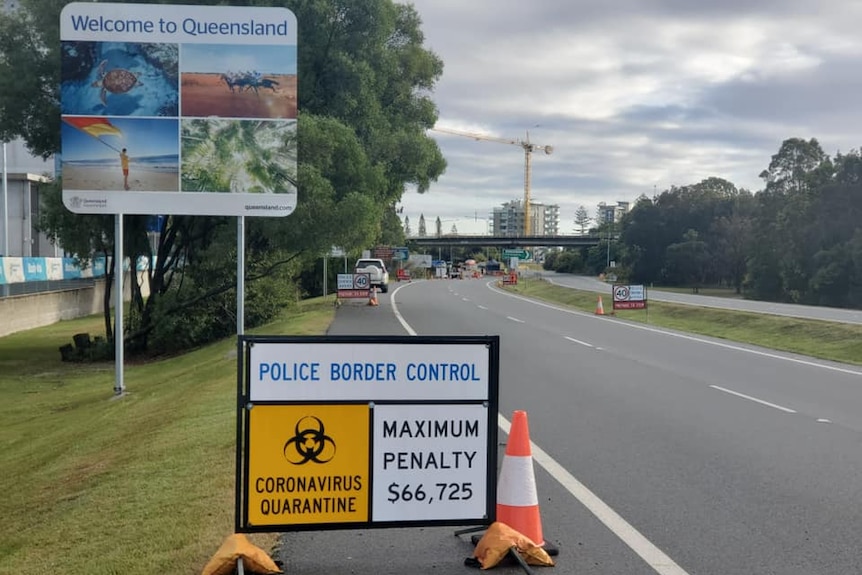 A Welcome to Queensland sign behind others saying border-control point and coronavirus quarantine.