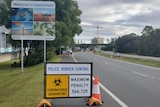 A Welcome to Queensland sign behind others saying border-control point and coronavirus quarantine.