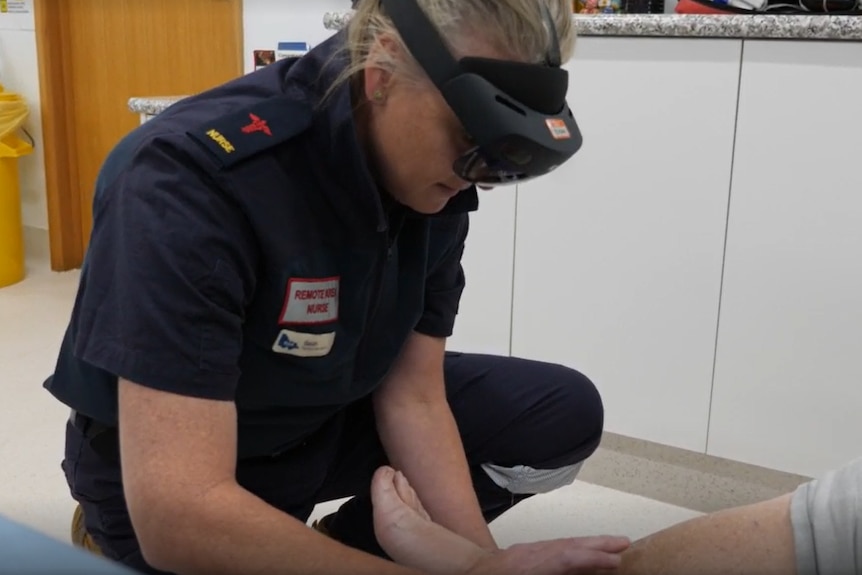 A nurse holds a patient's leg while holding a headset.