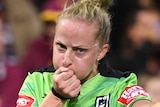 A female NRL referre blows a whistle in her right hand and points to the ground with an outstretched left arm.