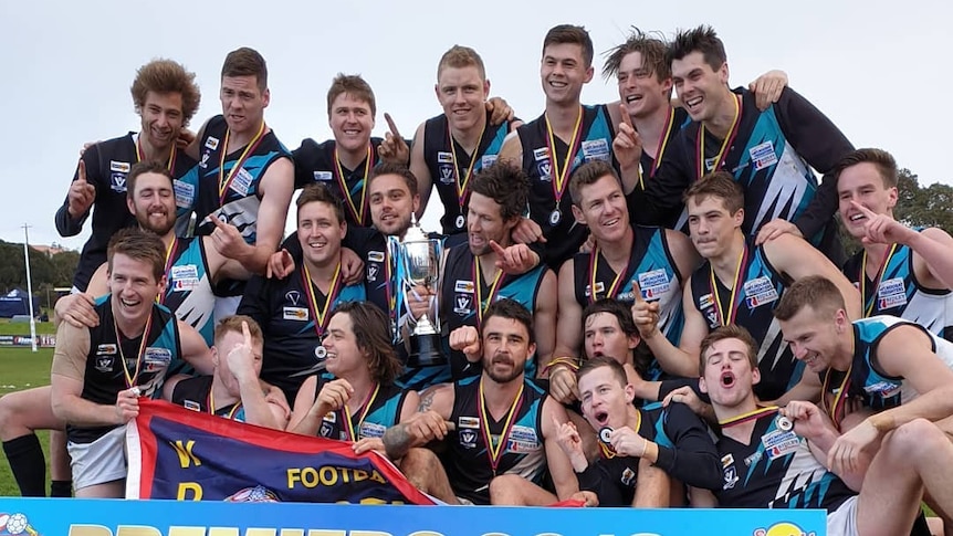 Kolora-Noorat's men's football team behind a banner reading 2019 premiers.