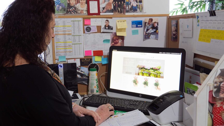 A woman standing in front of a computer looking at an online florist website