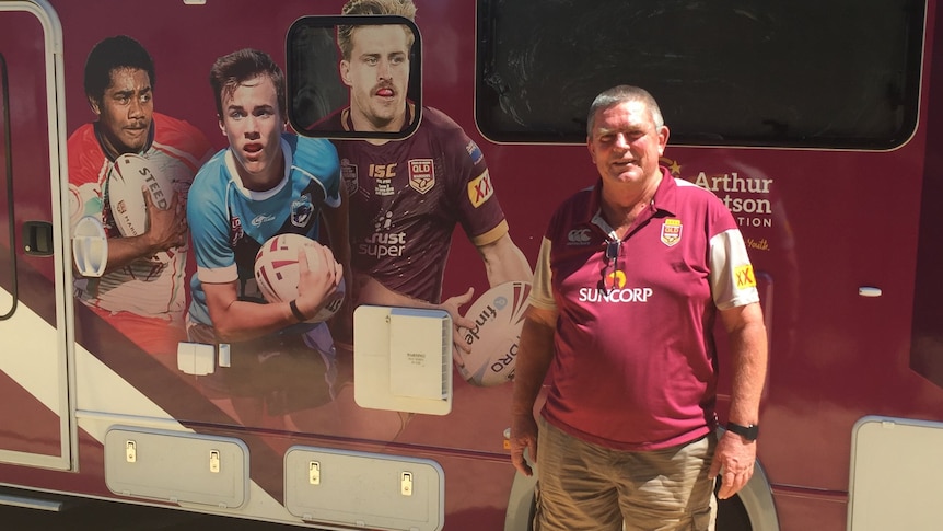 A man standing in front of a maroon van with player pictures on it