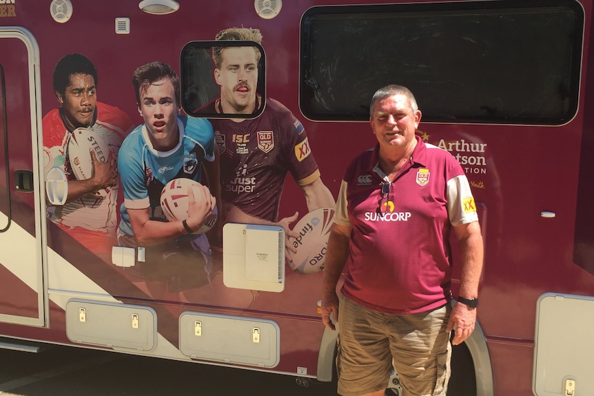 A man standing in front of a maroon van with player pictures on it