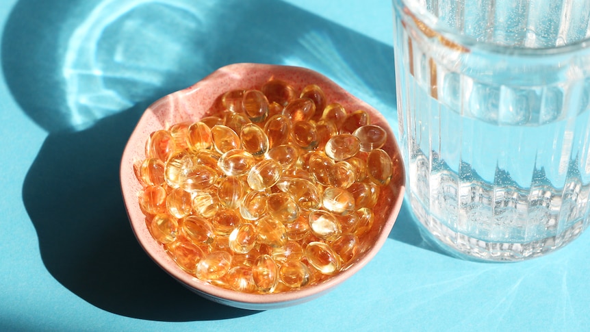 Bowl of golden tablets with glass of water