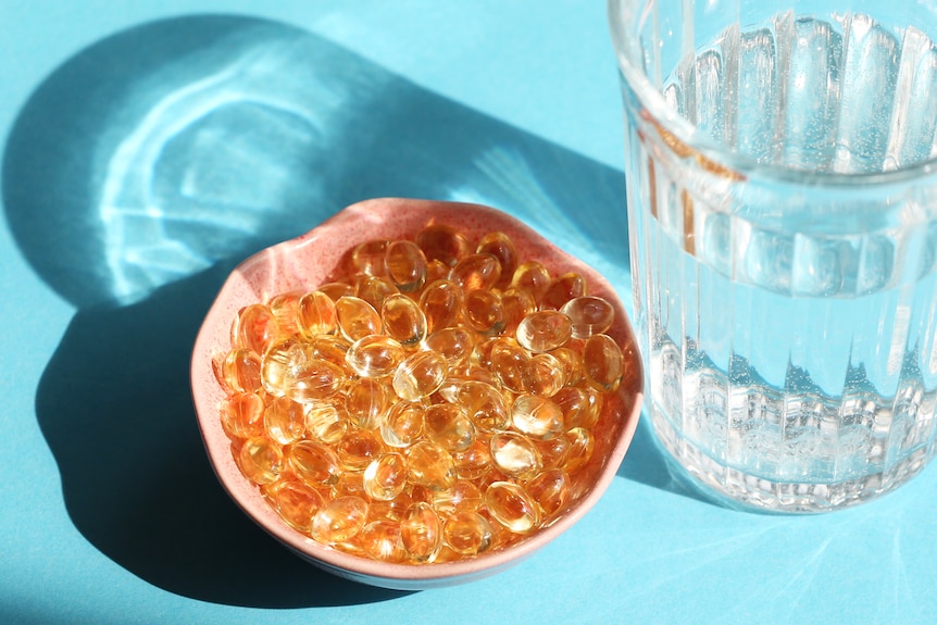 Bowl of golden tablets with glass of water