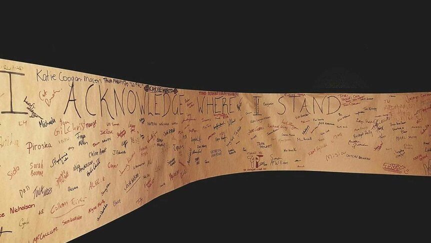 A long piece of butcher's paper with the words I ACKNOWLEDE WHERE I STAND written on it in marker pen, surrounded by signatures.
